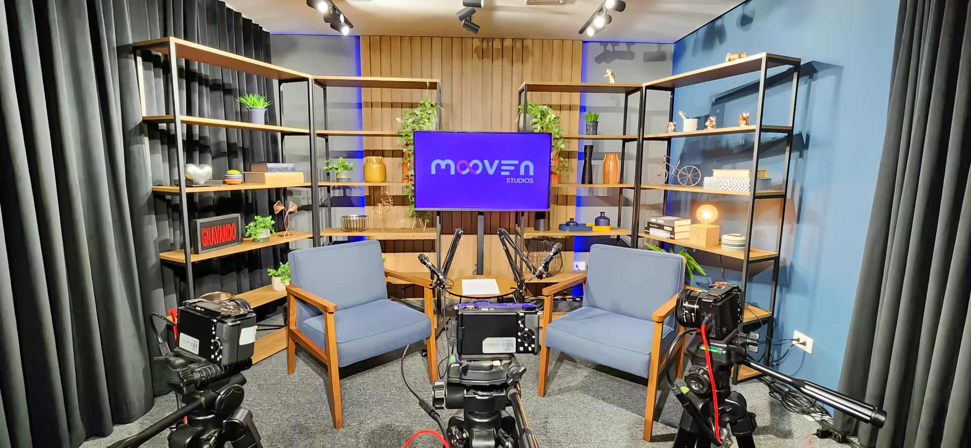 Cenário com duas poltronas frente a frente montado para conversa em formato talk show